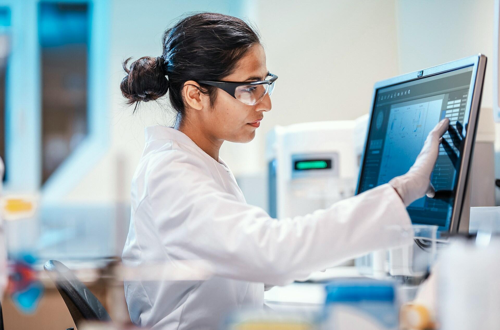 A person in lab safety gear at a computer.