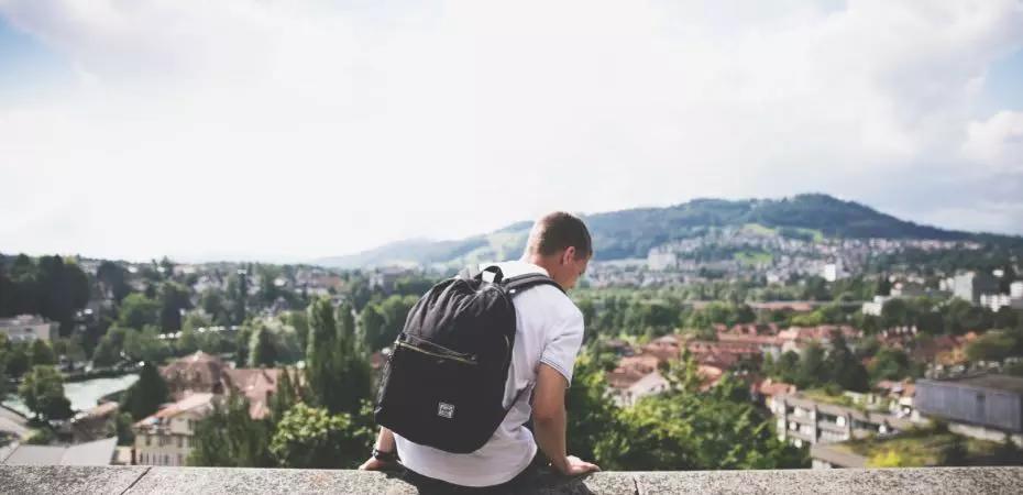 Homem de mochila sentado em um mirante
