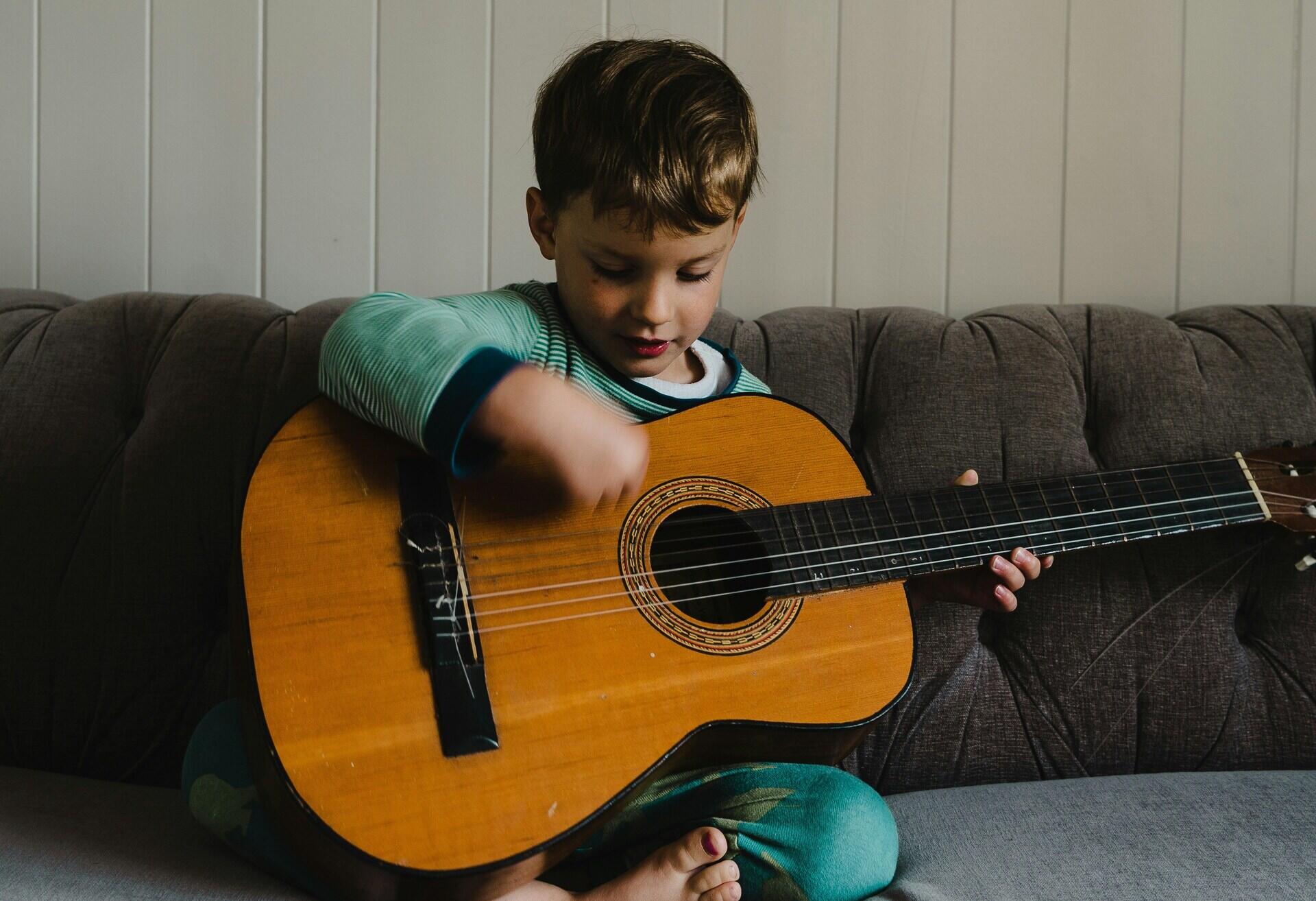 Criança no sofa tocando violão