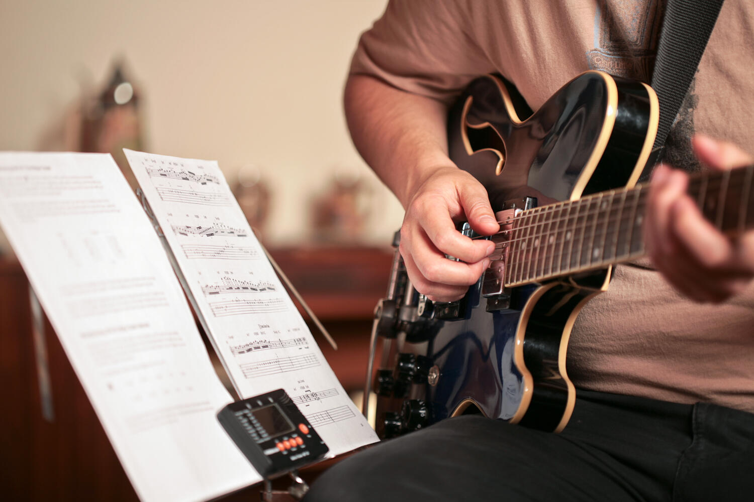 Homem sentado tocando guitarra.