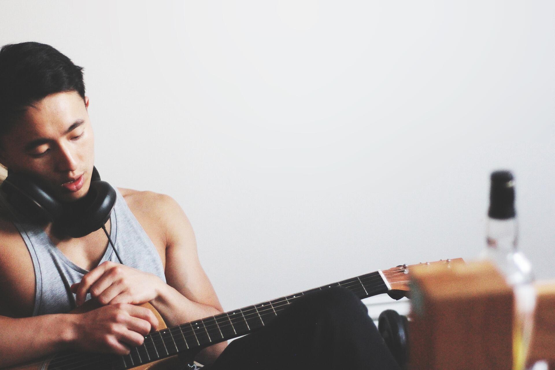 Homem sentado segurando uma guitarra.