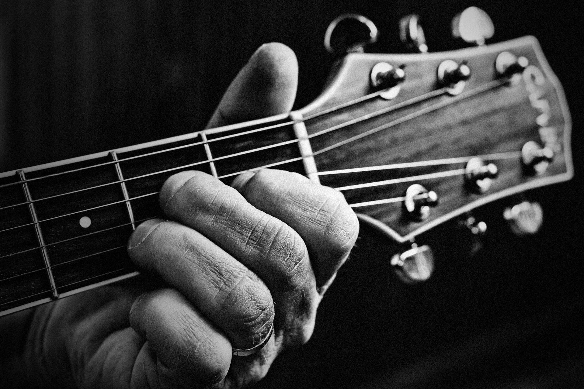 Fotografia a preto e branco de homem tocando guitarra.