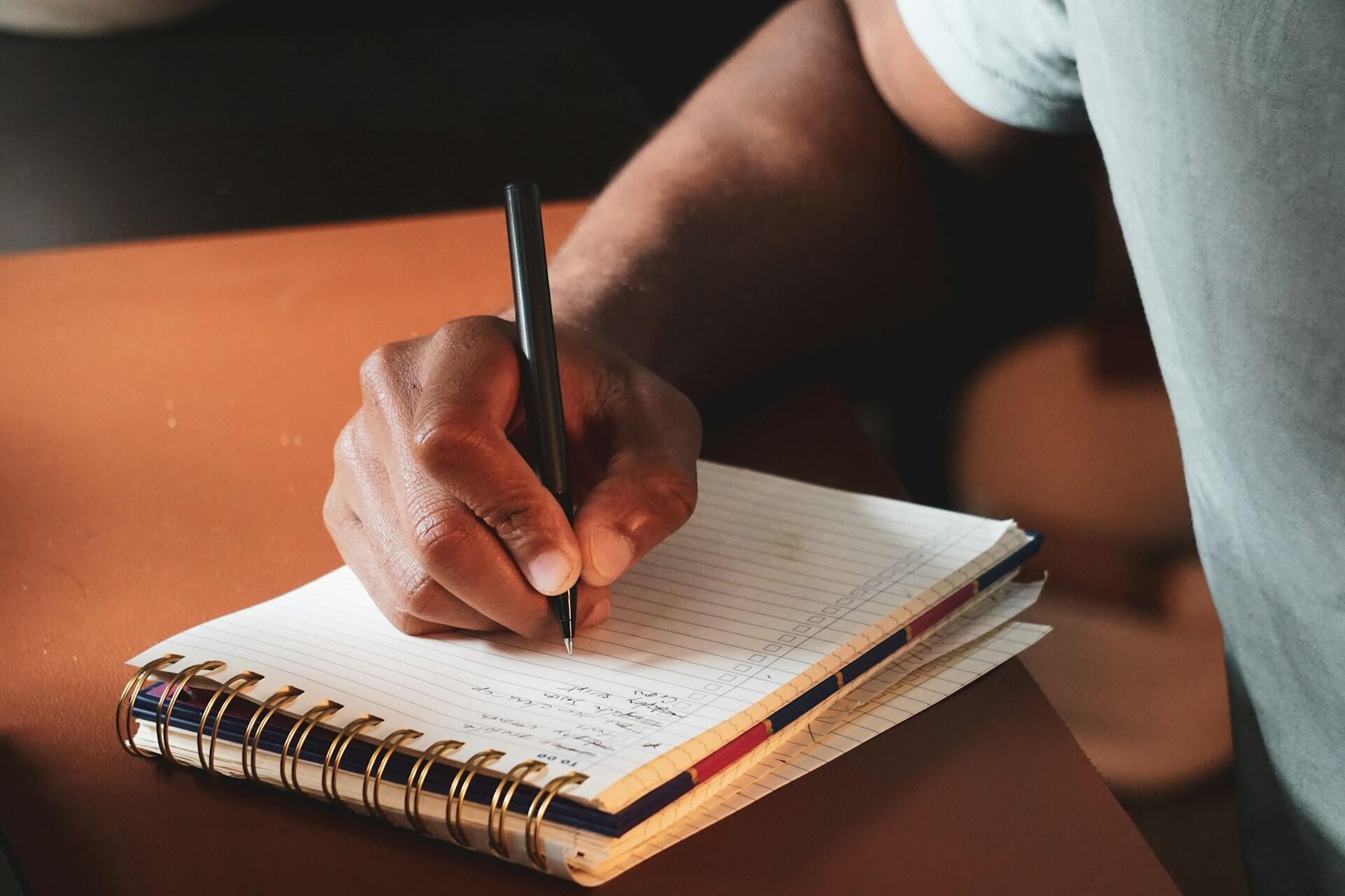 Imagem de um homem tomando notas em um caderno.