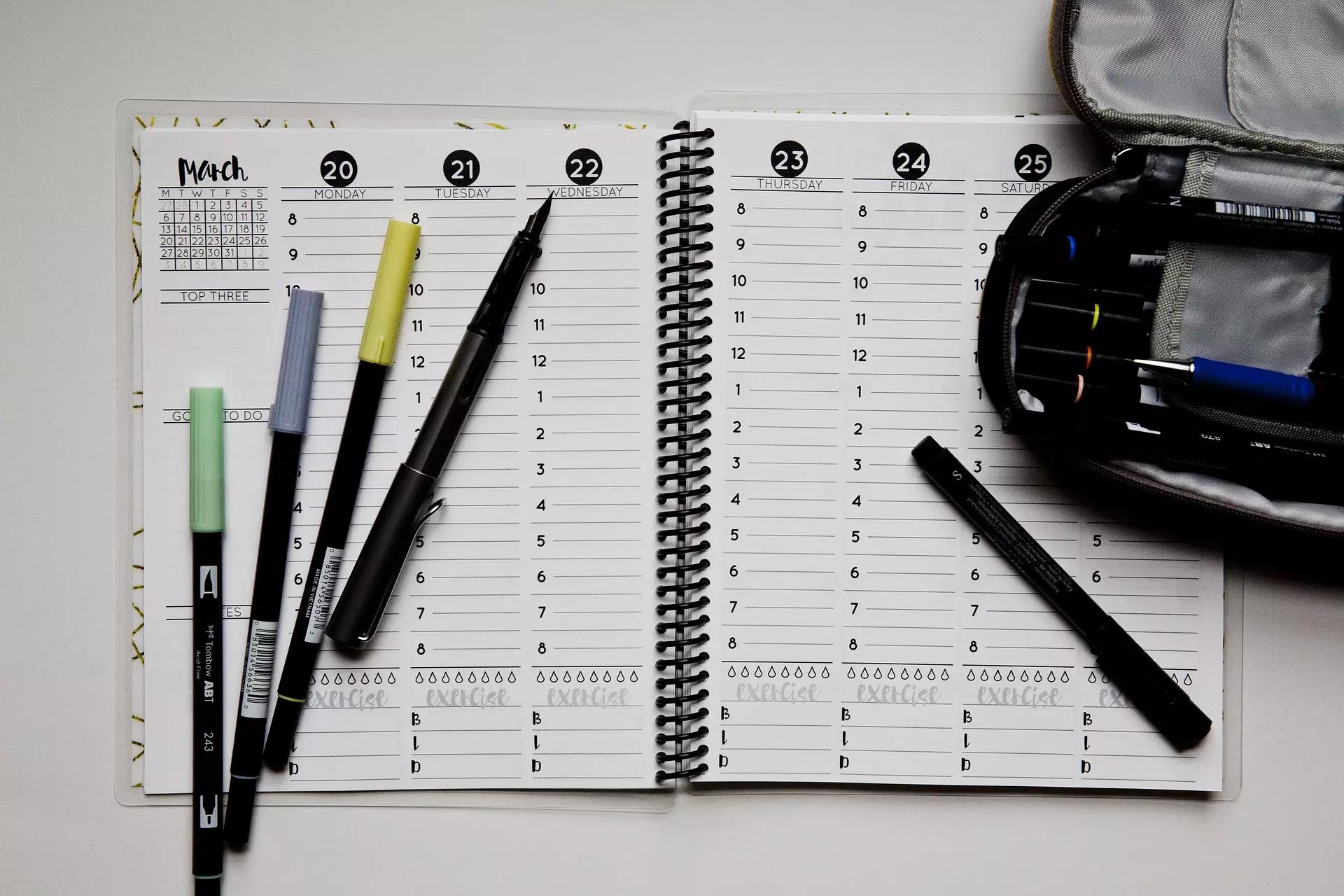 Agenda com canetas de cores variadas.
