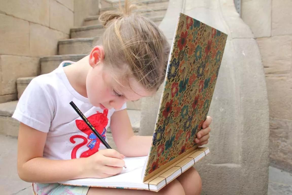 Menino desenhando em seu caderno.