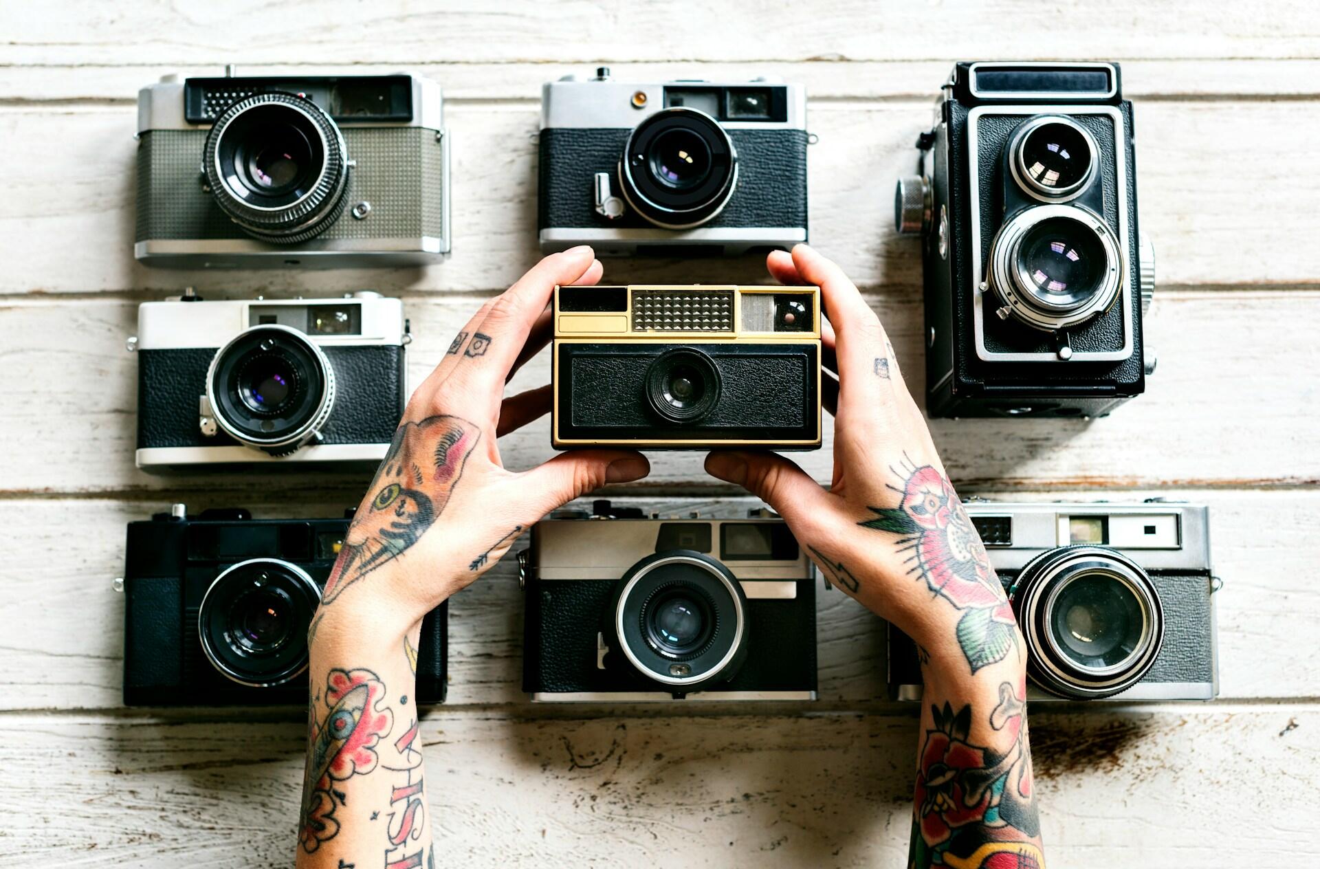 Diferentes cameras fotográficas expostas e uma mão segurando um modelo