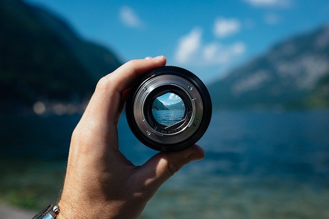 Mão segurando lente de máquina fotográfica.