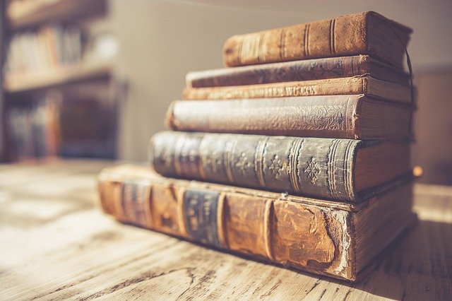 Livros antigos empilhados sobre a mesa.