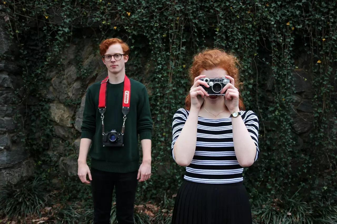 Dois jovens ruivos com máquinas fotográficas.