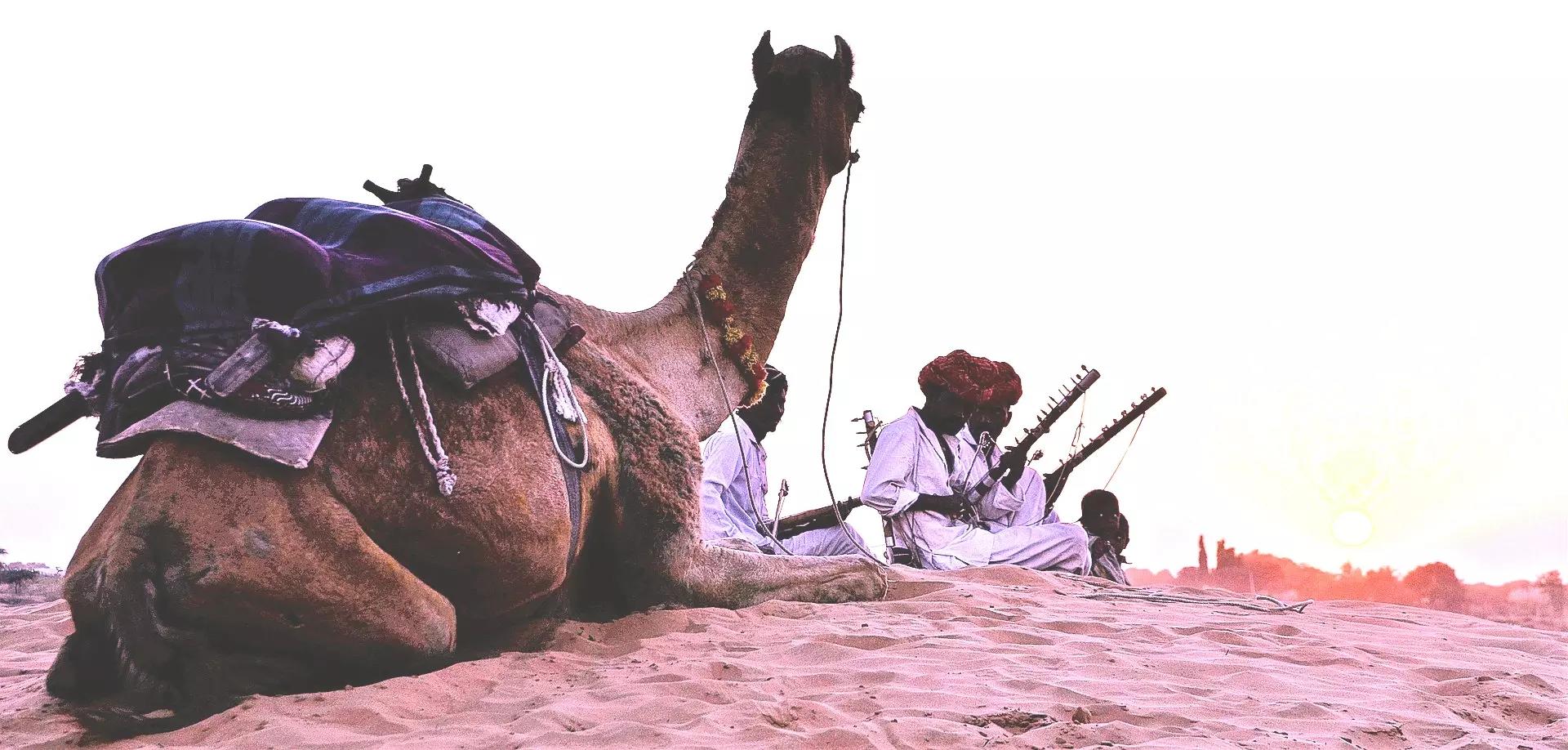Camelo ao lado de homens e crianças no deserto