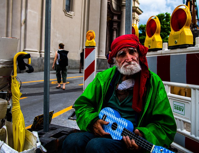 Homem idoso toca ukelele azul na rua.