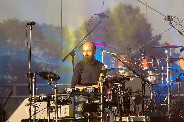 Baterista barbudo e careca tocando em show.