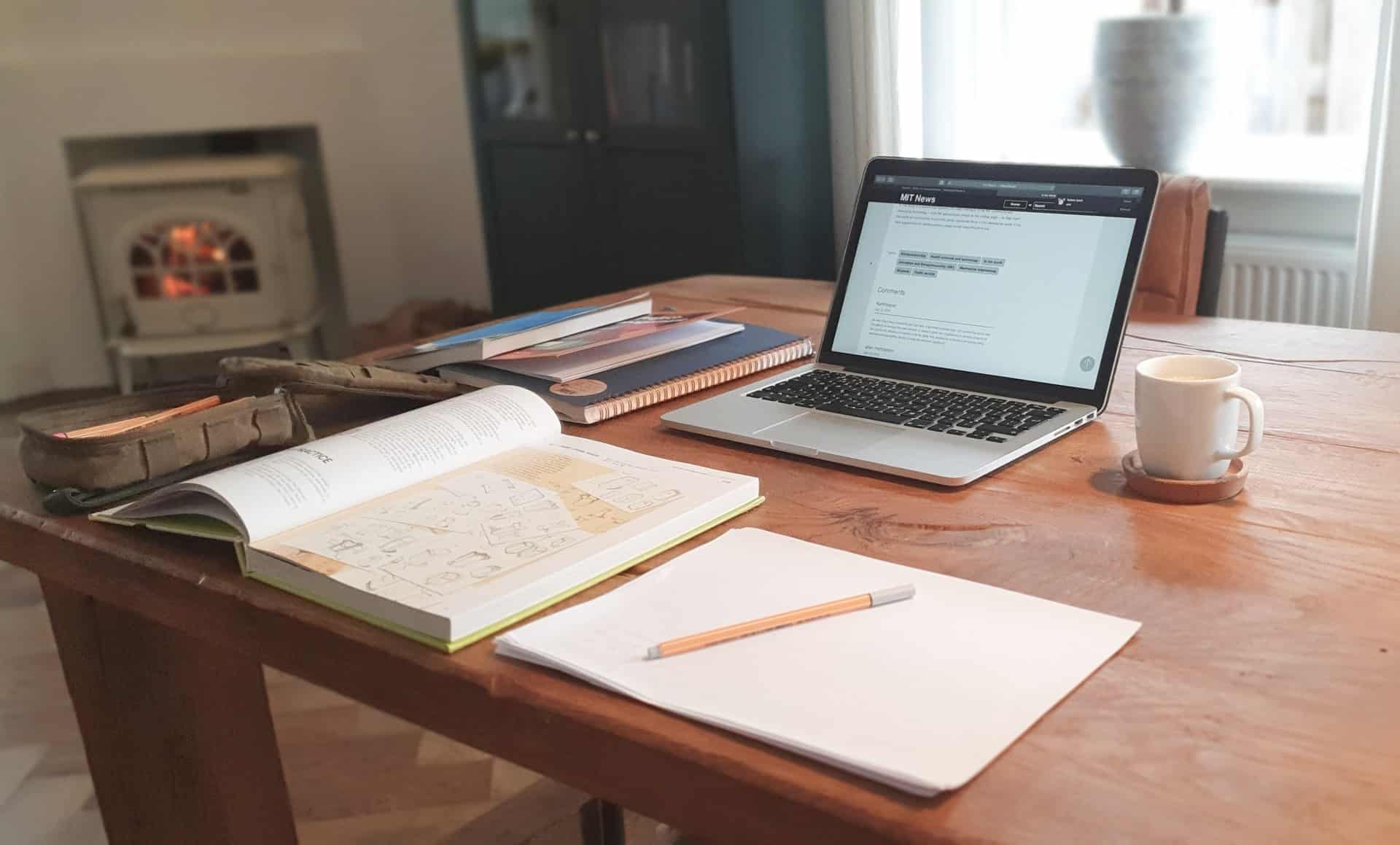 computador e livros abertos em uma mesa 