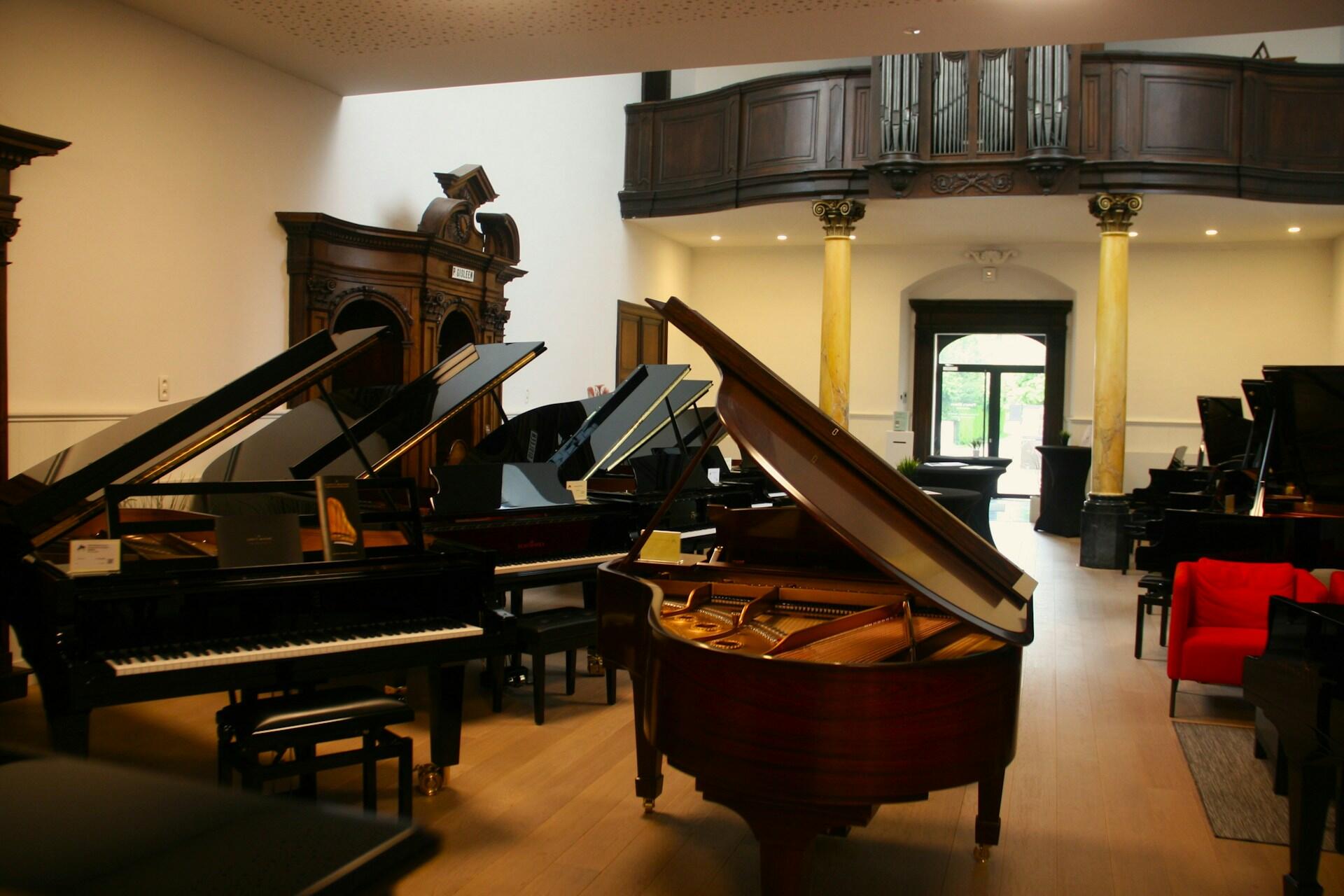 Imagem de uma sala cheia de pianos de cauda.