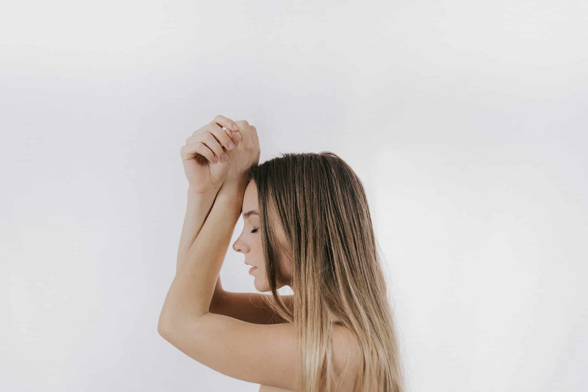 mulher com as mãos sobre o rosto e olhos fechados