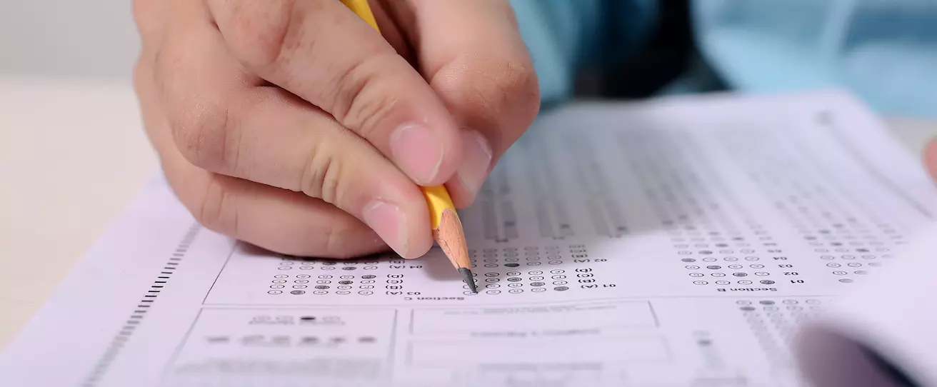 mão segurando um lápis e marcando respostas em uma prova de múltipla escolha