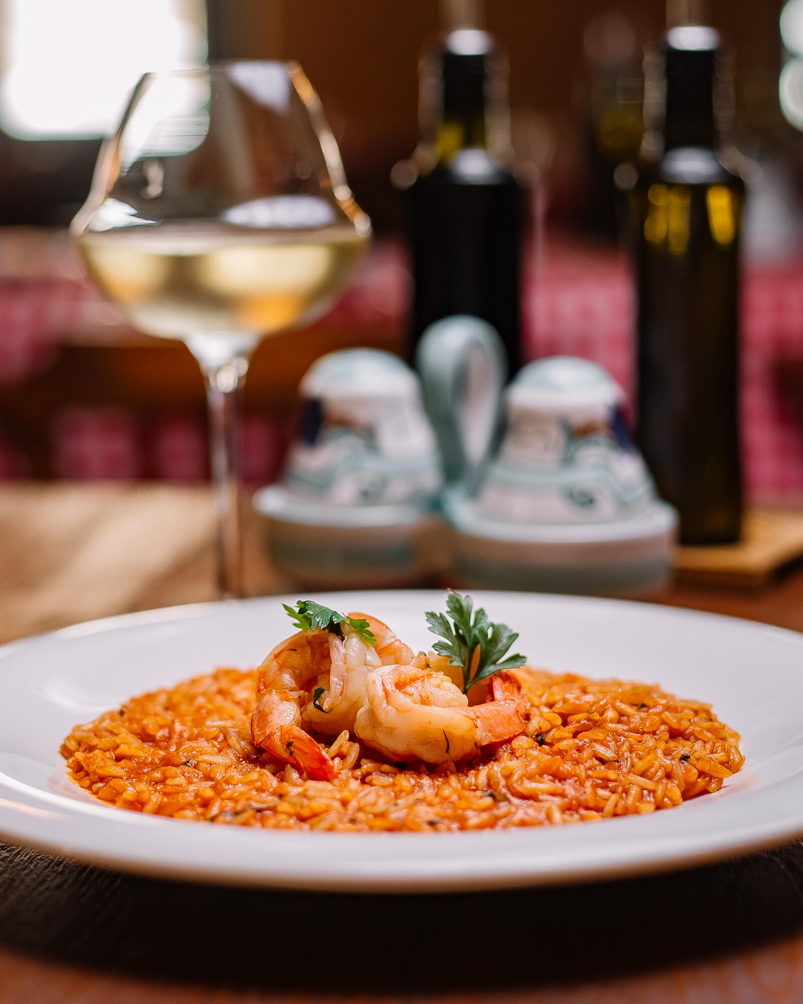 Prato de risoto de camarão com vinho em cima da mesa.