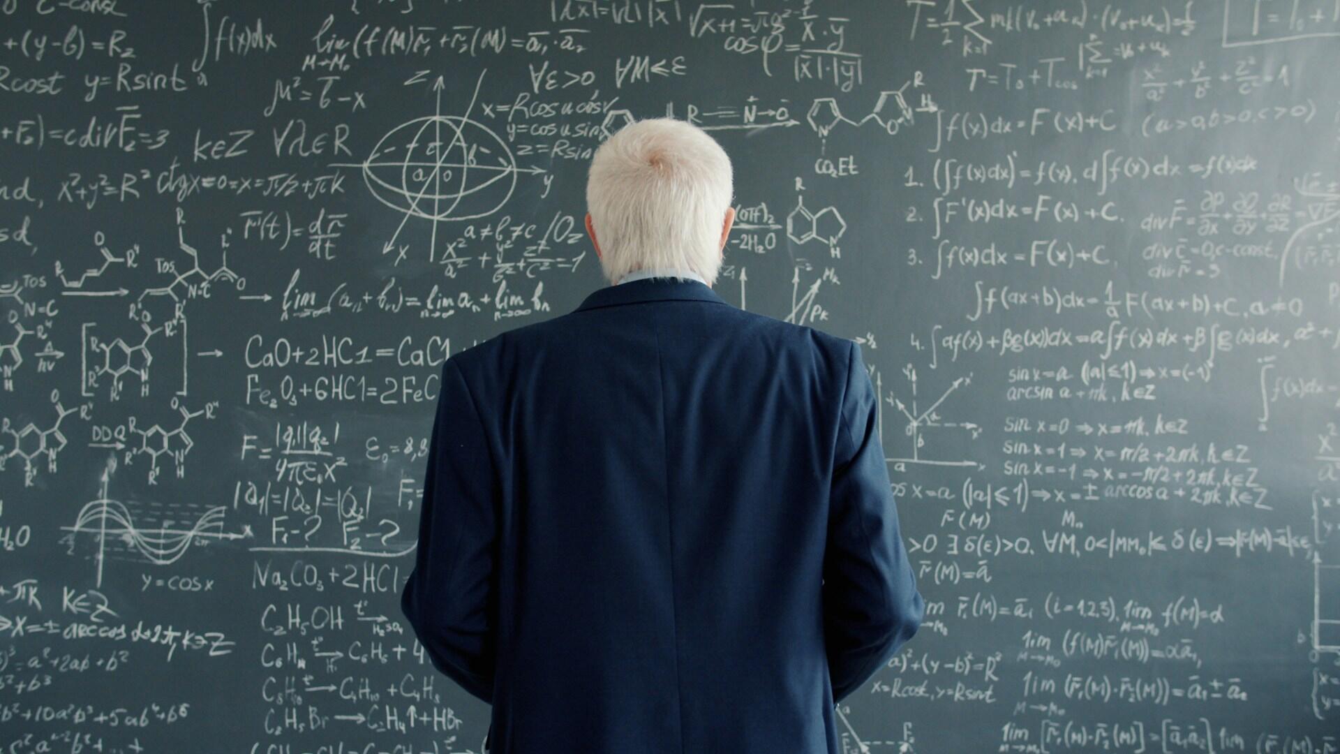 Especialista em Física observando um quadro escolar.