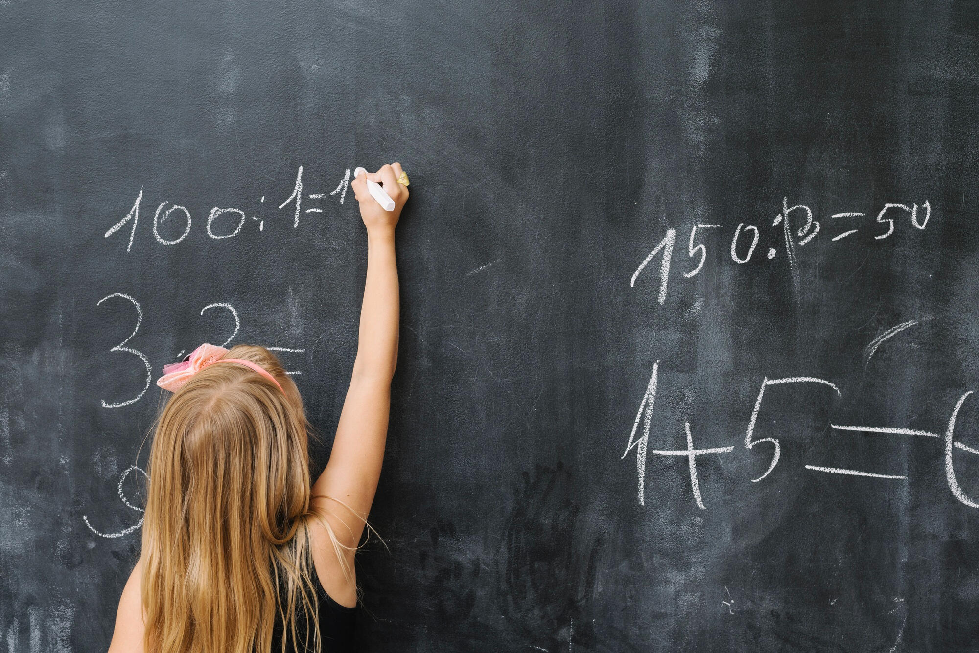 Estudante desenvolvendo cálculos matemáticos, usando a lousa. 