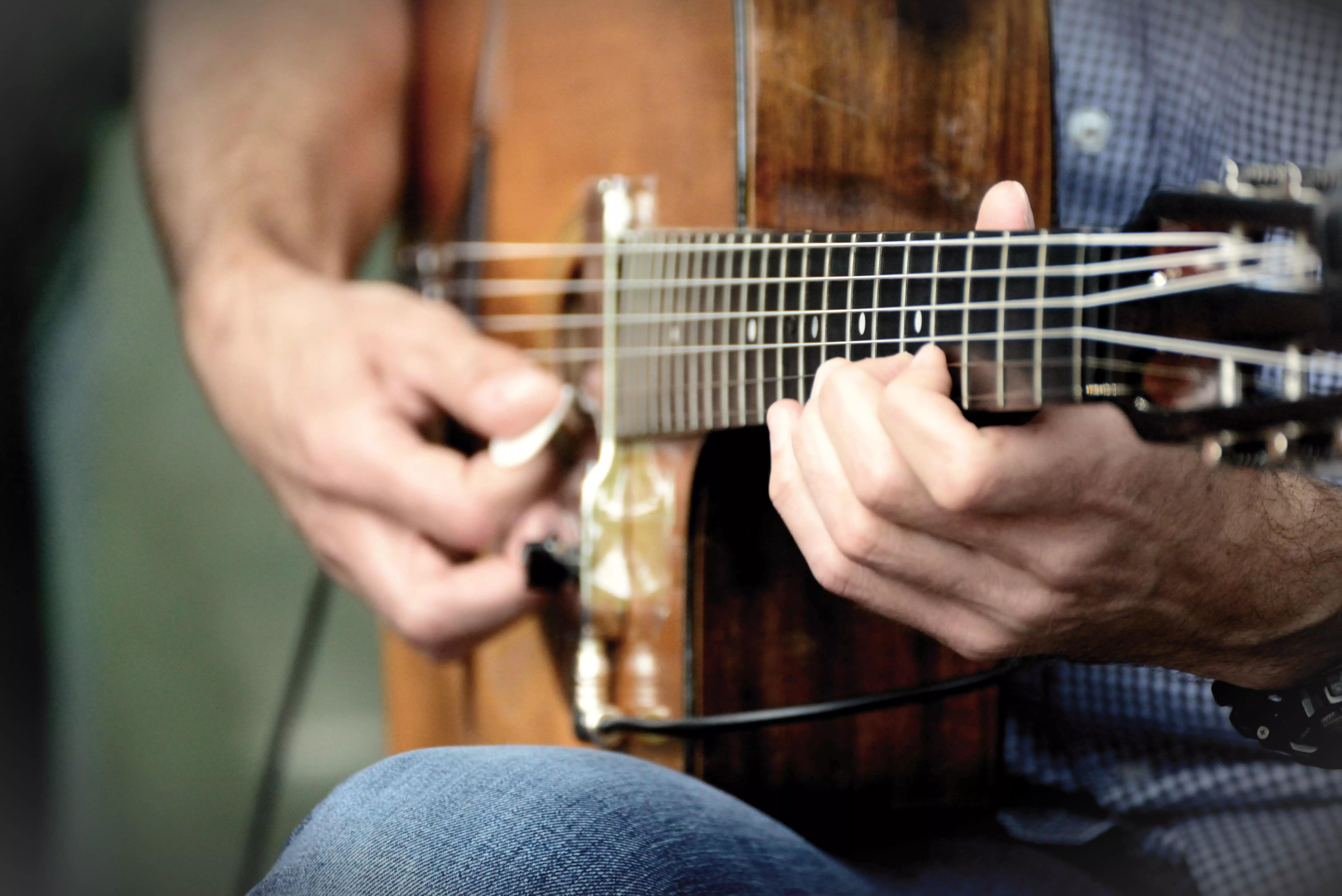 Pessoa tocando violão com palheta