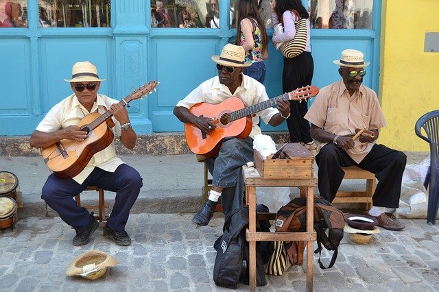 Tres homens tocam violão na rua