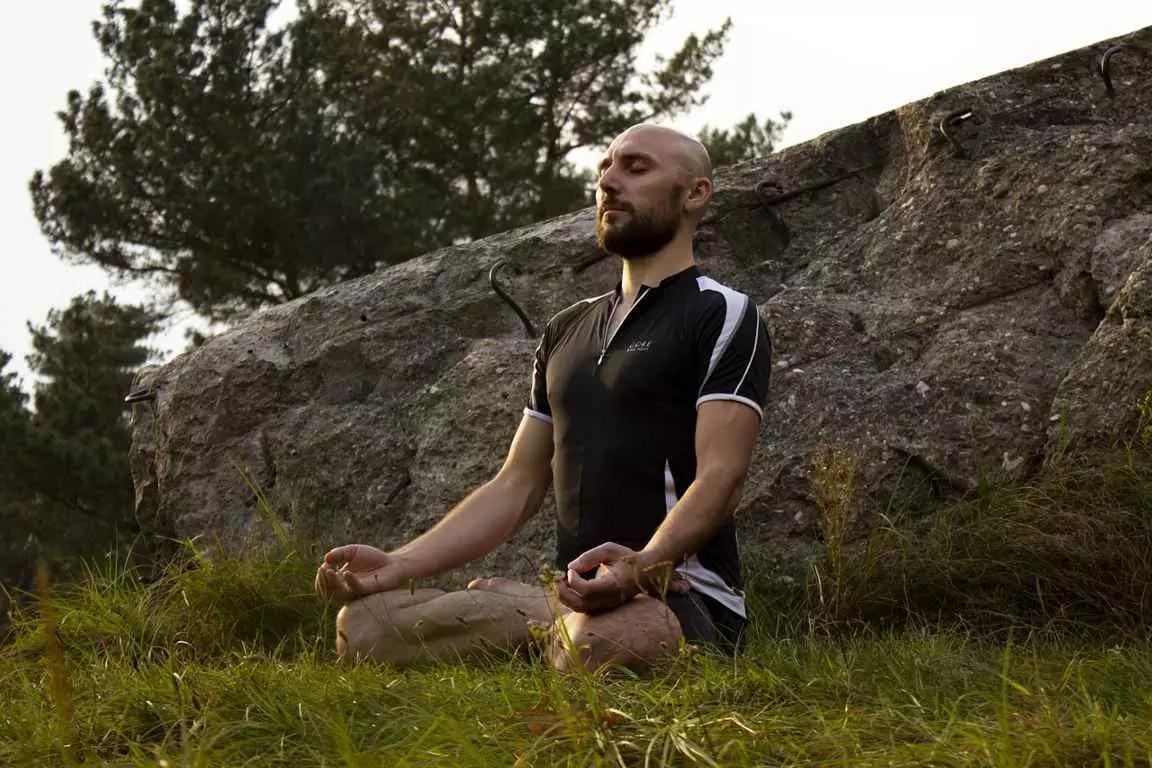 homem sentado em posição de lótus em um jardim