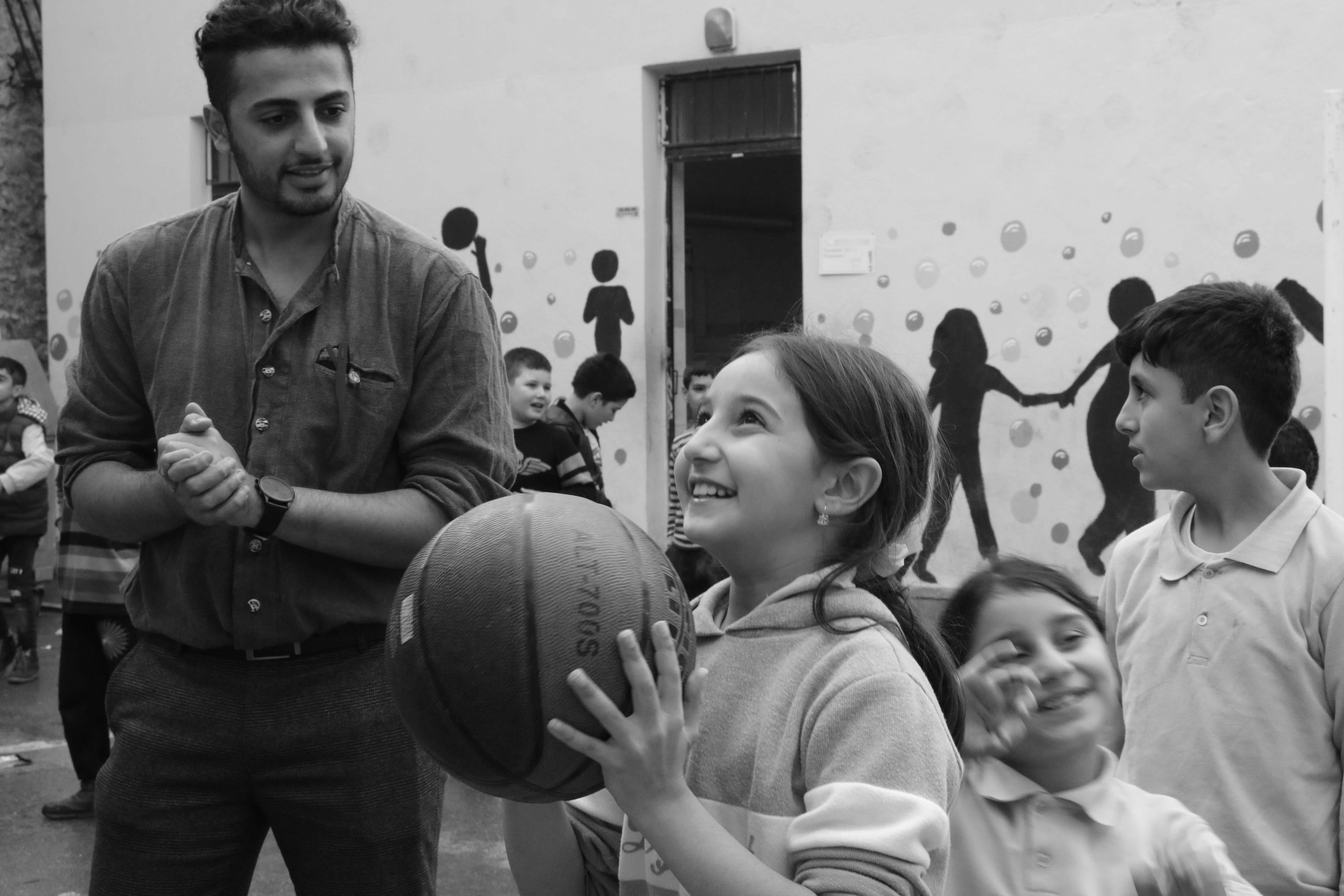 Crianças jogando basquete com um professor