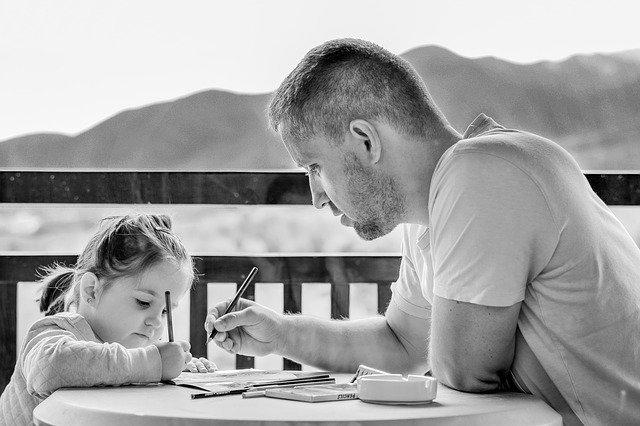 Pai e filha estudam juntos na varanda.