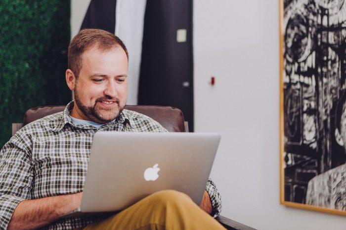 Um professor mexendo em seu laptop para dar aulas.