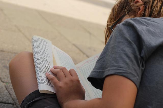 Menino lendo livro sentado no chão.