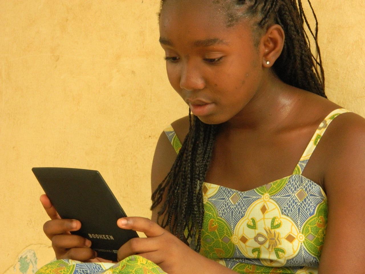 Uma menina segurando um tablet em sua mão.