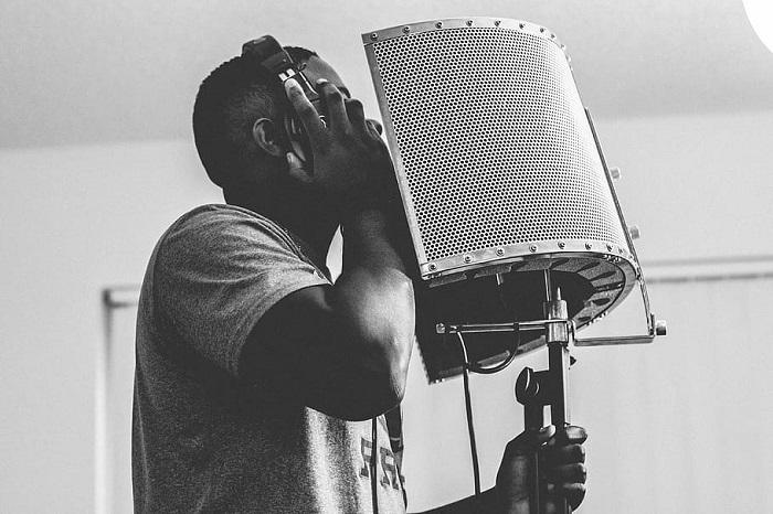 Um homem negro cantando em frente ao microfone