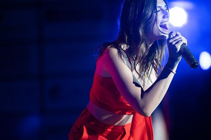 Uma mulher de vestido vermelho cantando no palco