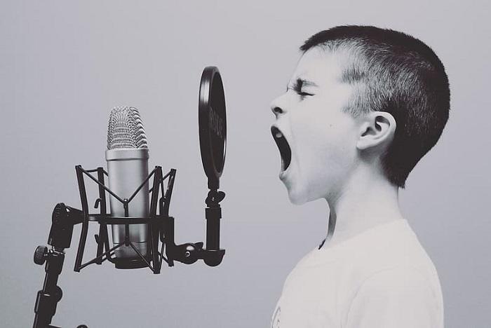 Um garoto cantando na frente do microfone