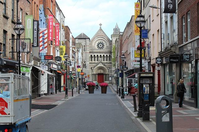 Rua com comércio e igreja ao fundo em Dublin