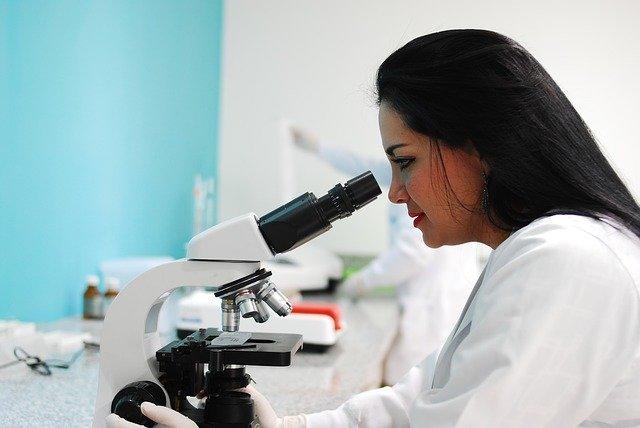 Cientista analisa amostra no microscópio em laboratório.