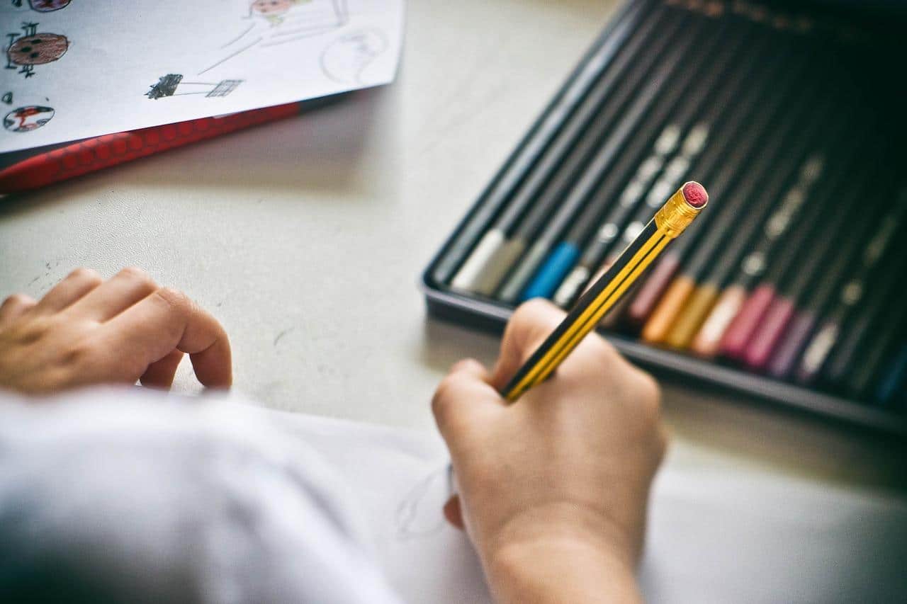Uma criança desenhando com lapis de cor