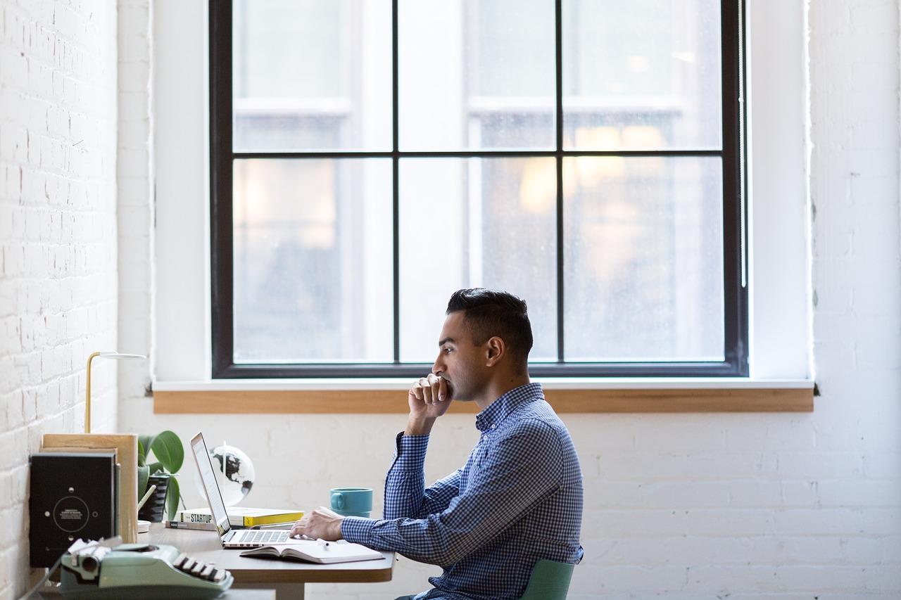 Em que ordem proceder para codificar um site? Homem em frente ao computador.