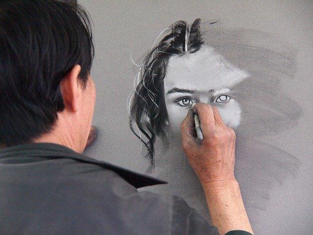 Artista desenha rosto de mulher em preto e branco.