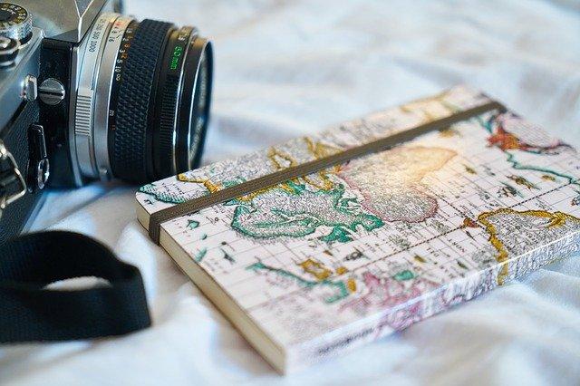 Caderno com mapa mundi e máquina de retrato sobre a mesa.