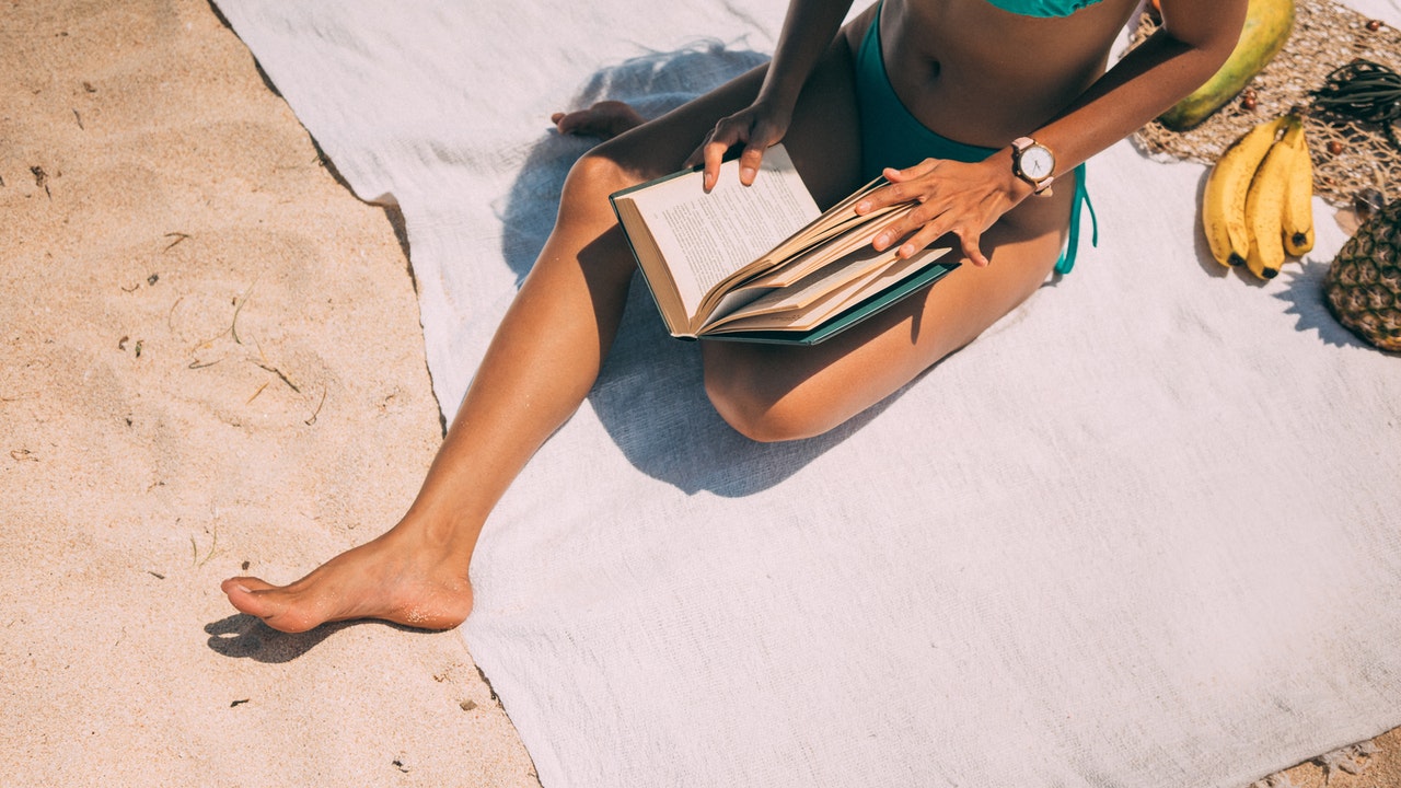 Mulher lê livro na praia