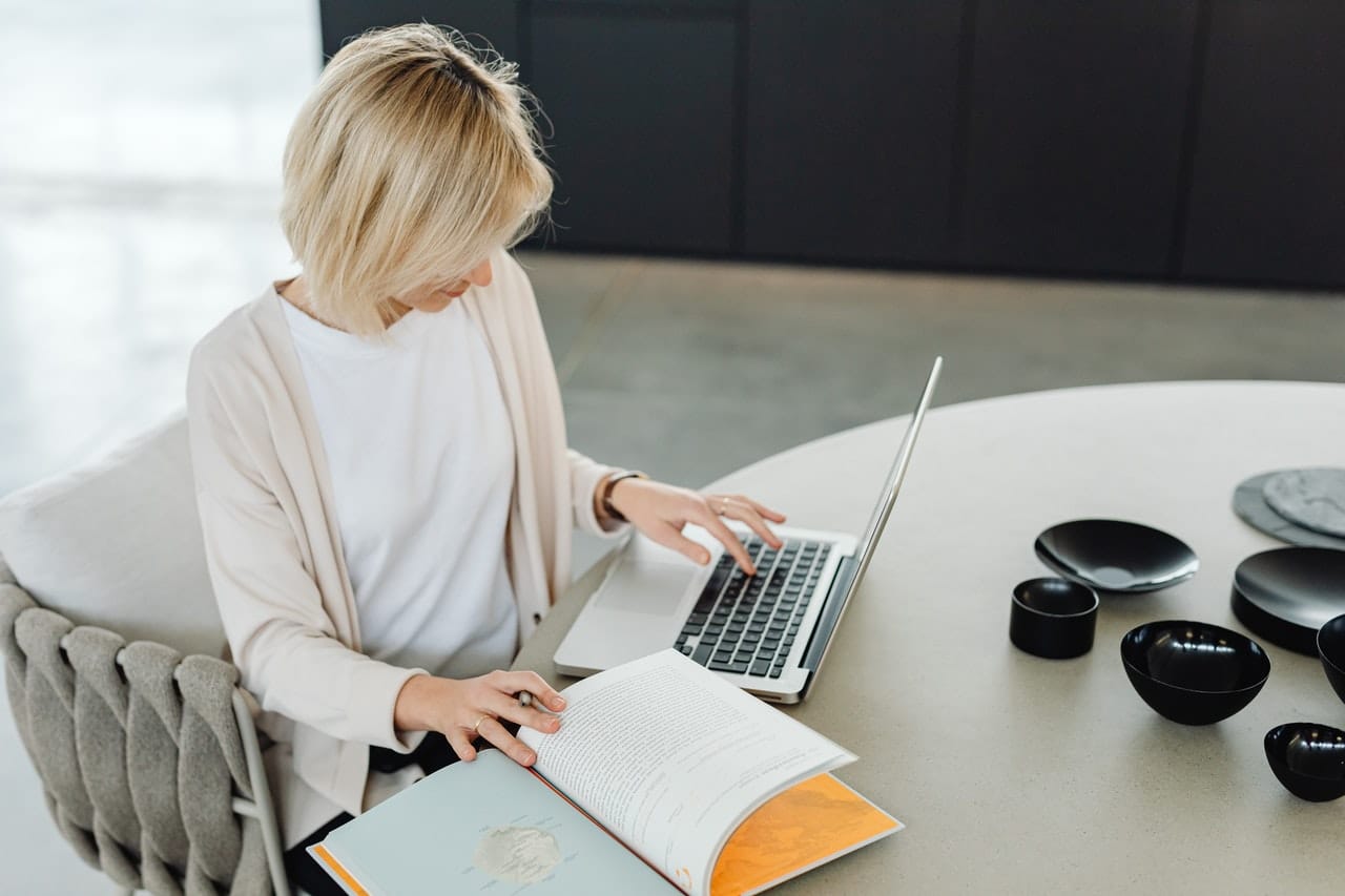 mulher trabalhando no computador com caderno ao lado