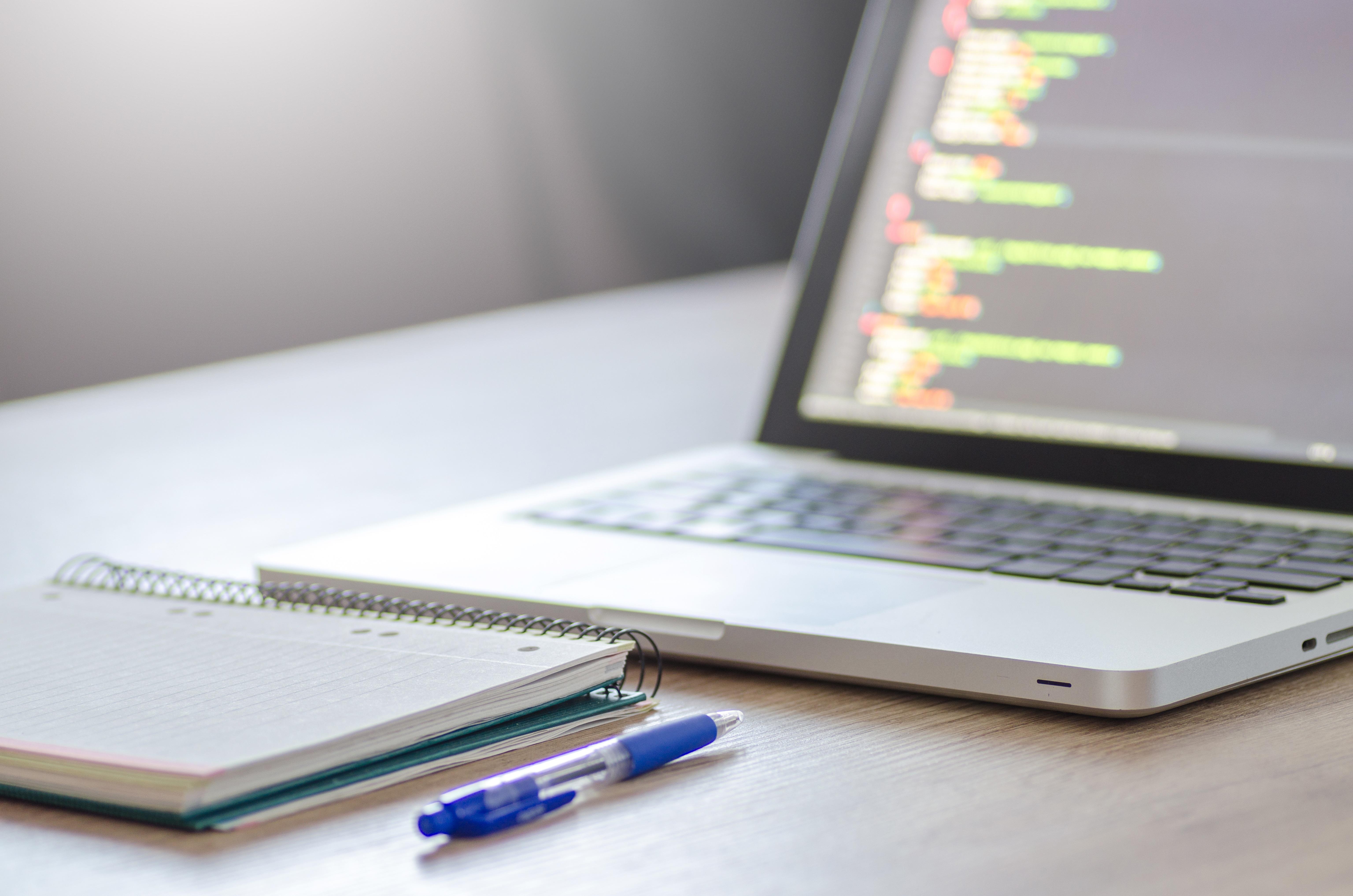 Códigos de linguagem de programação no computador, caderno e caneta