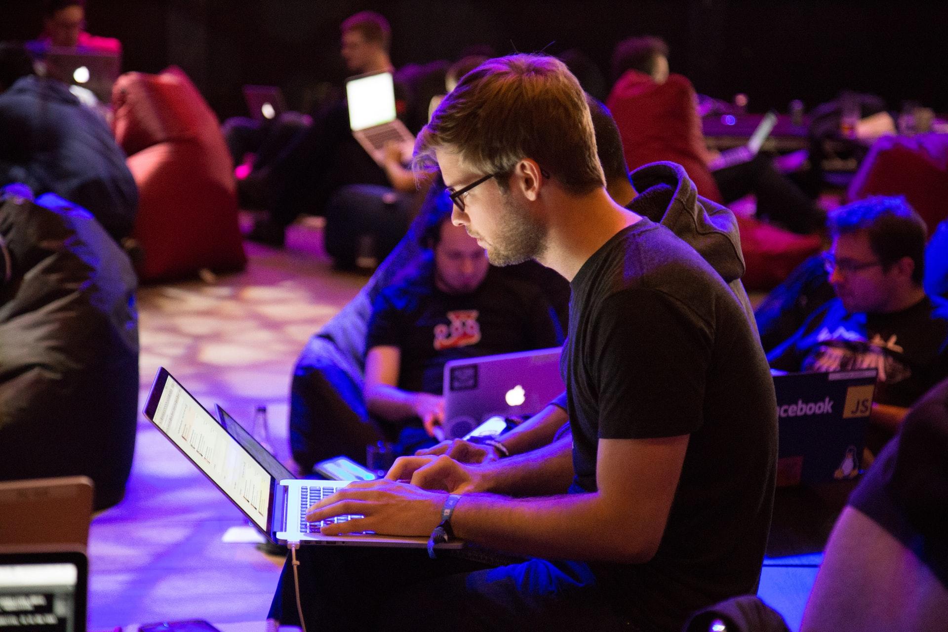 Sala com vários programadores trabalhando em seus notebooks.