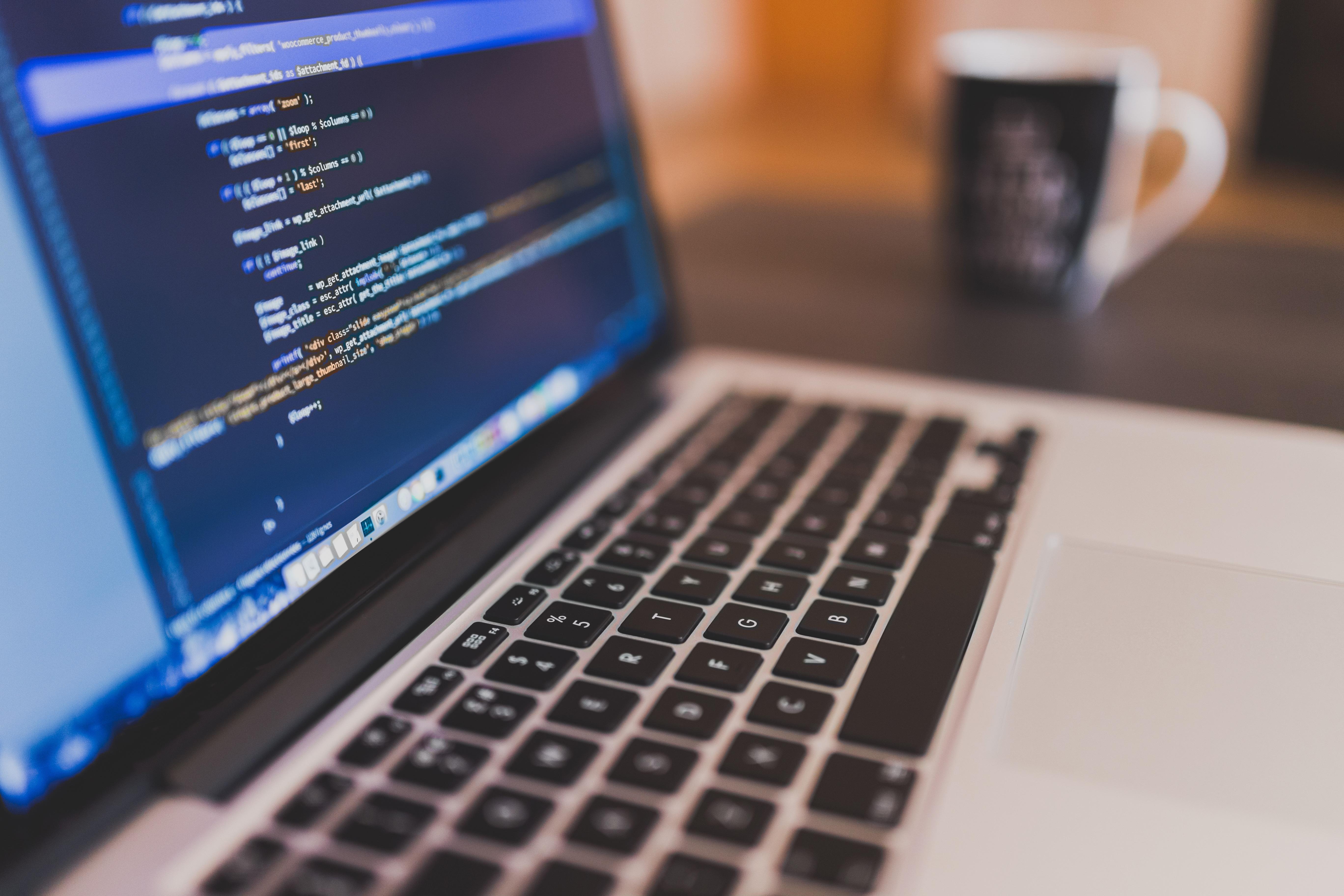 Tela do notebook com linguagem de programação e xícara