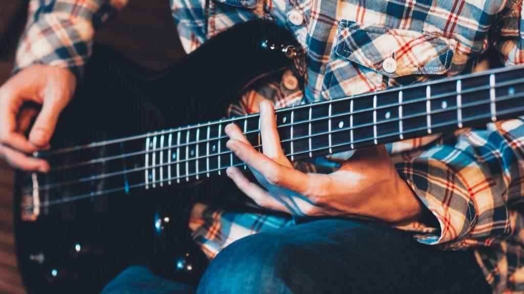 Mãos de um homem tocando contrabaixo.