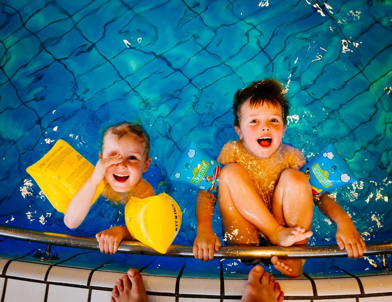 Duas crianças nadando com boias na piscina