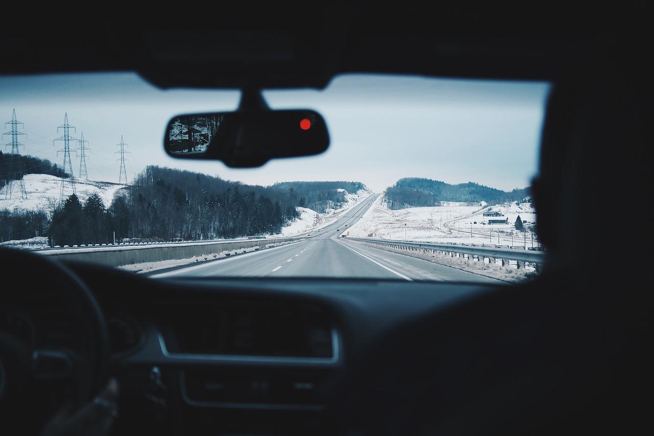 Dois homens em um carro em uma estrada com neve.