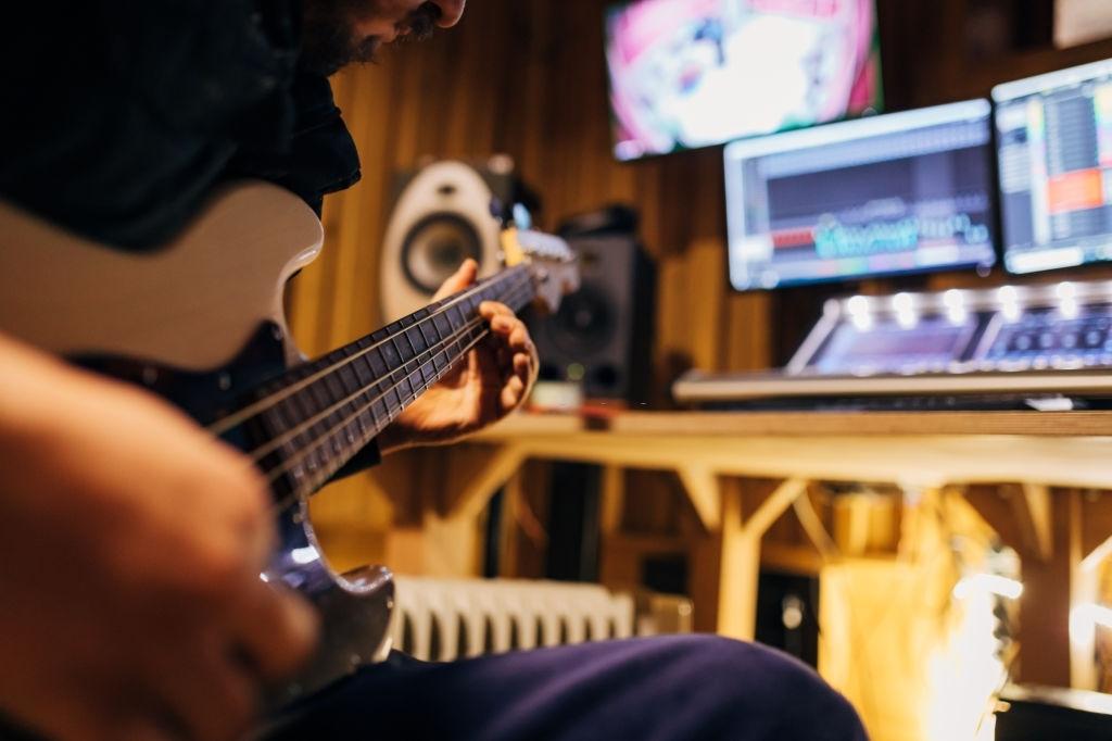 Baixista gravando em estúdio de música aconchegante e bem equipado.