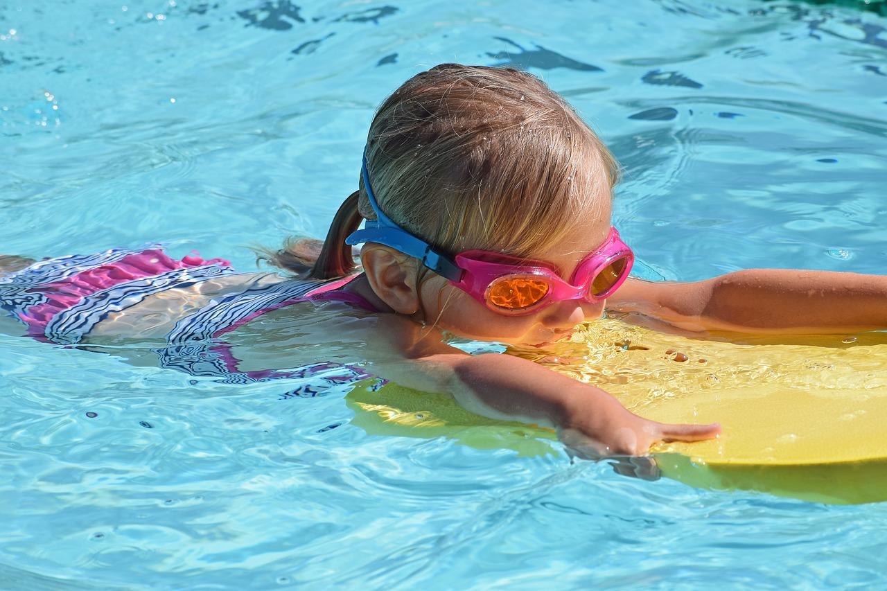 Menina nadando em piscina com prancha